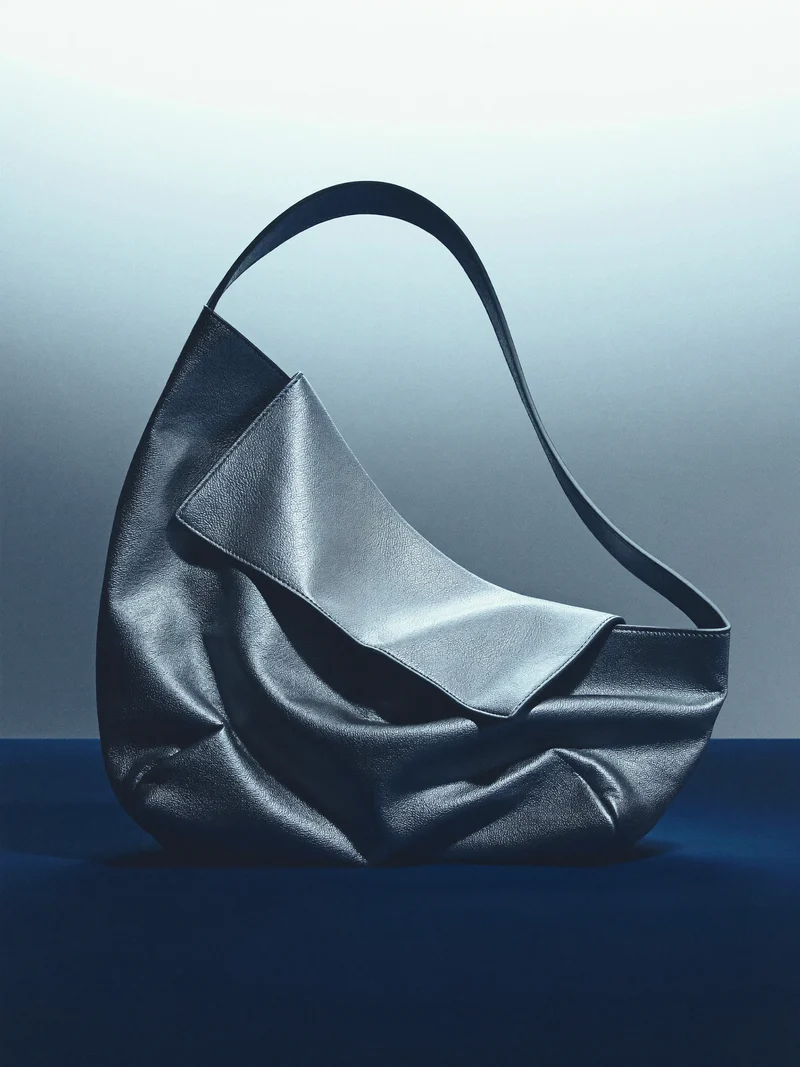 Illustration einer asymmetrisch gefalteten Leder-Schultertasche ohne Logos