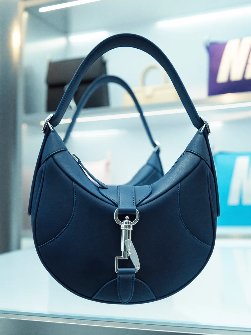 Illustration einer kompakten Halbmond-Crossbody mit originellem Verschluss